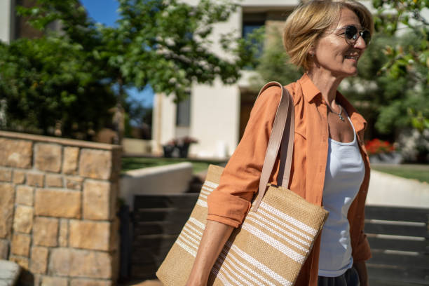 Mature woman with a bag in front of her beautiful house.
