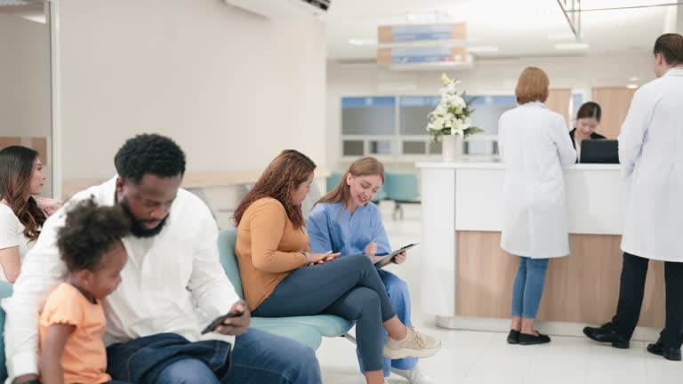 Two Caucasian male and female doctors are walking to greet a female hospital receptionist