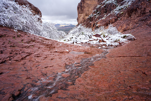 Snow melt flows down the smooth landscape on Siphon Draw Trail during a winter storm in the Superstition Mountains at Lost Dutchman State Park