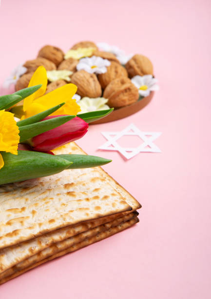 istock Passover Greeting Card with Matzah, Nuts and Spring Flowers on Pink Background. 1470990017