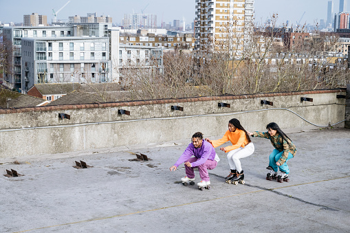 Professionals in 20s and 30s practicing on urban garage rooftop with southeast London residential district in background.