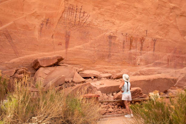 Woman inspects ancient rock art panel Buckhorn pictographs Utah stock photo
