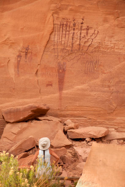 Woman inspects ancient rock art panel Buckhorn pictographs Utah stock photo