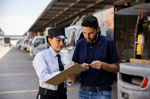 Female security guard checking the documents of a truck driver working at a distribution warehouse
