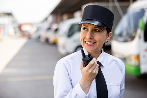 Portrait of a female security guard working at a distribution warehouse and talking on a walkie-talkie