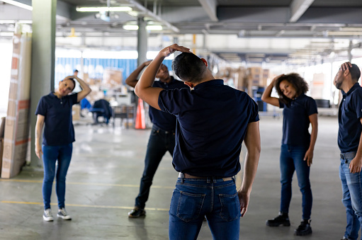 Group of Latin American workers stretching on an active pause while working at a warehouse