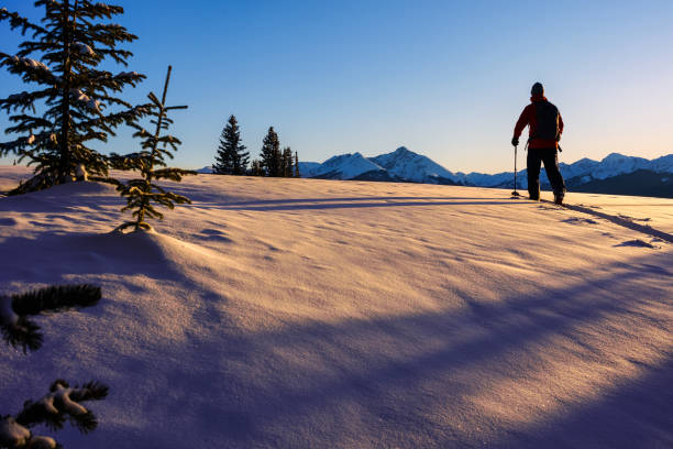 Outdoor Adventure Ski Touring with Scenic Mountain Backdrop - Man recreating on alpine touring skis while skiing high on mountain ridge with scenic views and warm sunset light.