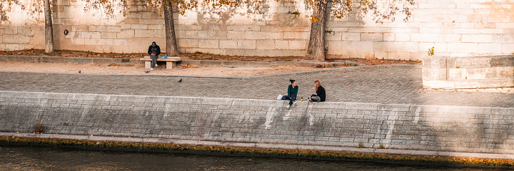 Teenagers sitting and chatting on the quays of the Seine river in Paris, France