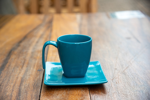 cup of coffee with saucer on a wooden table outside