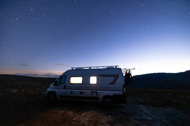 istock A camper van illuminated from inside standing on a high plateau, starry night without moon at night. 1471003754