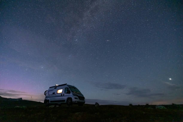 istock A camper van illuminated from inside standing on a high plateau, starry night without moon at night. 1471004945