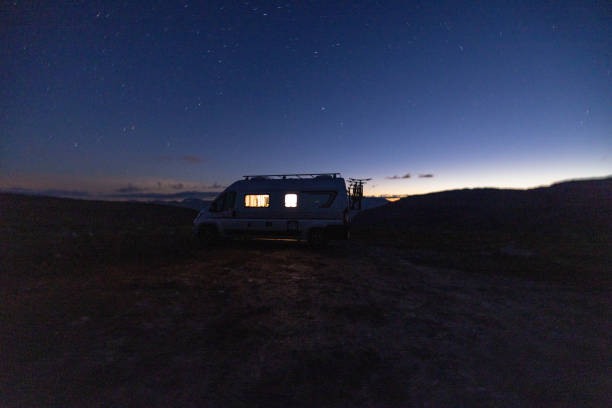 istock A camper van illuminated from inside standing on a high plateau, starry night without moon at night. 1471005078
