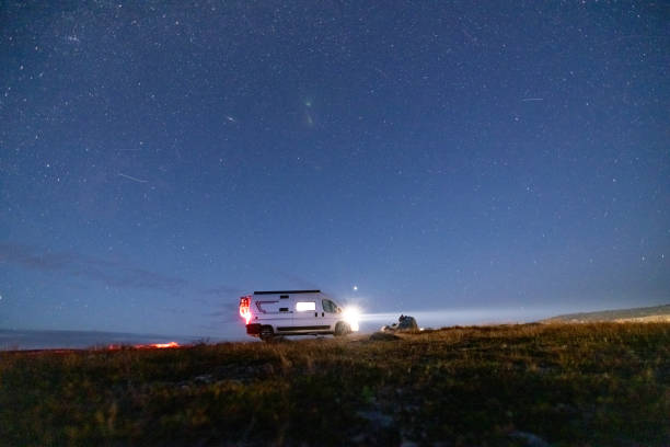 istock A camper van illuminated from inside standing on a high plateau, starry night without moon at night. 1471005190