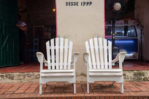 Two chairs in front of the entrance to an ice cream parlor in the city of Mompox. Bolivar Department. Colombia. June 3, 2022.