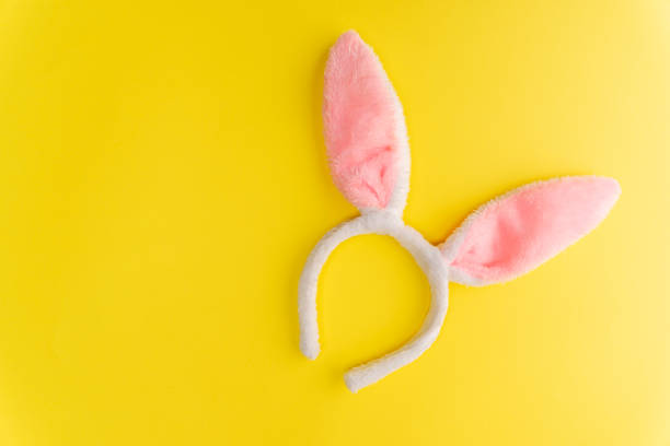 soft fur hoop with pink rabbit ears on a yellow background stock photo
