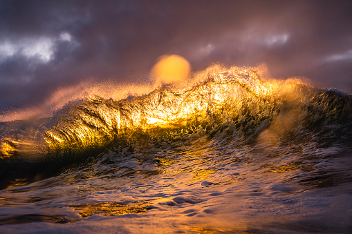 Unique ocean waves colliding in early morning golden light with dramatic sky. Shot on the south east coast of Australia.