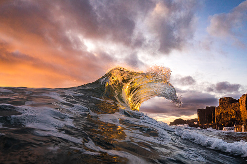 Powerful ocean waves erupting in early morning golden light with dramatic sky. Shot on the south east coast of Australia.