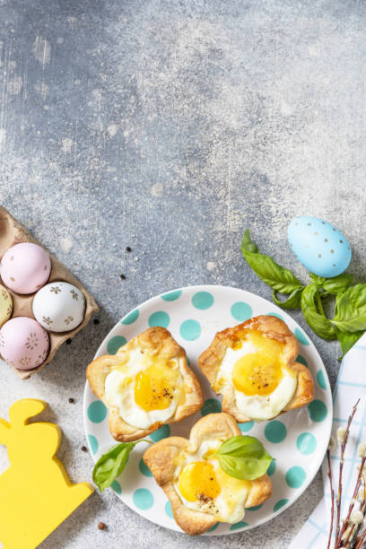 istock Easter breakfast idea. Scrambled eggs in puff pastry with cheese and bacon on a stone background. View from above. Copy space. 1471015245