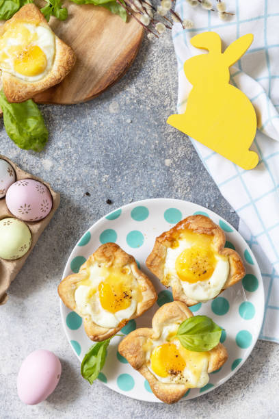 istock Easter breakfast idea. Scrambled eggs in puff pastry with cheese and bacon on a stone background. View from above. Copy space. 1471015246