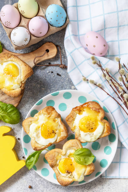 istock Easter breakfast idea. Scrambled eggs in puff pastry with cheese and bacon on a stone background. View from above. 1471015251