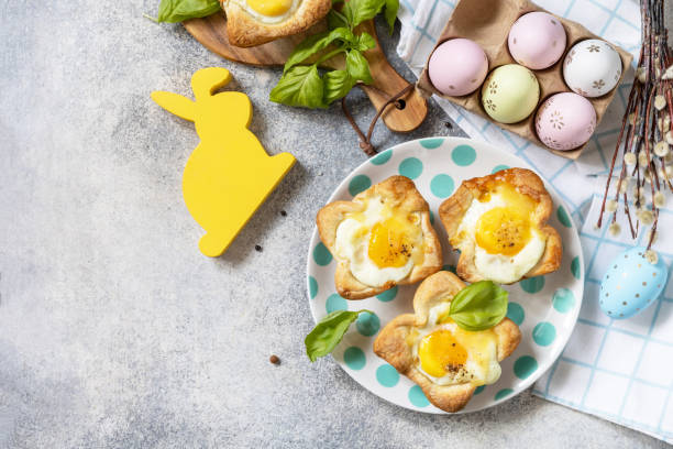 istock Easter breakfast idea. Scrambled eggs in puff pastry with cheese and bacon on a stone background. View from above. Copy space. 1471015255