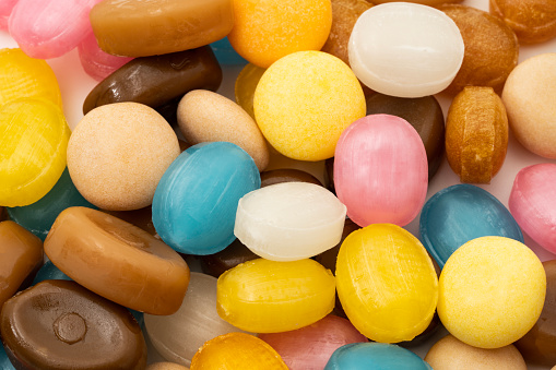 Color image depicting an overhead view of an arrangement of bowls filled with an assortment of multi-colored sweets. Room for copy space.