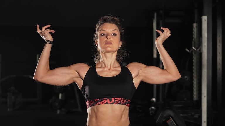 Muscular woman flexing her muscles in the gym