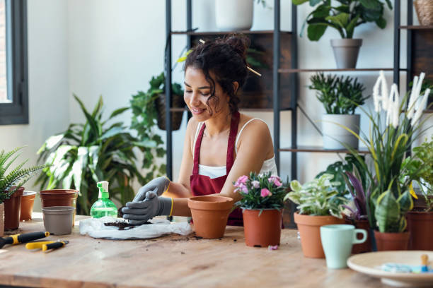 istock Influencer woman arranging plants and flowers while recording a tutorial video with smartphone in a greenhouse 1471031782
