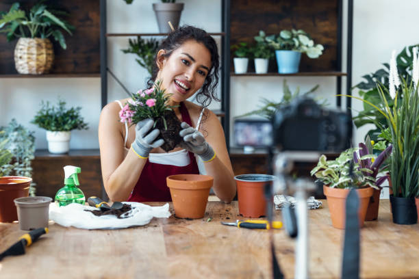 istock Influencer woman arranging plants and flowers while recording a tutorial video with smartphone in a greenhouse 1471031791