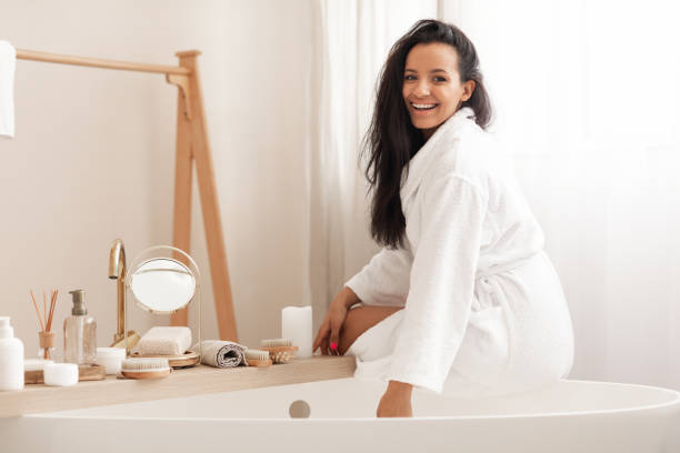 istock Cheerful Attractive Lady Wearing Bathrobe Sitting On Bathtub In Bathroom 1471032148