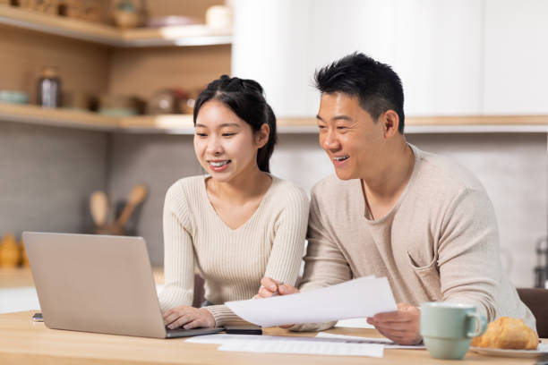 istock Cheerful asian couple paying bills on Internet, using laptop 1471032168