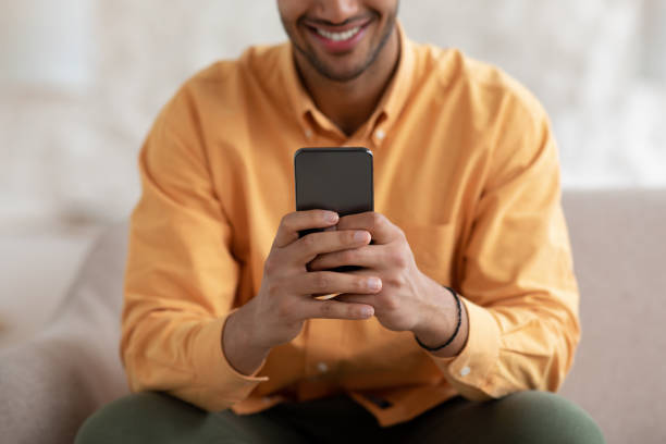 istock Smiling young man using smartphone at home, close up 1471032691