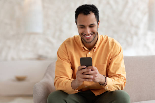 istock Portrait of smiling Arab man using smartphone at home 1471032697