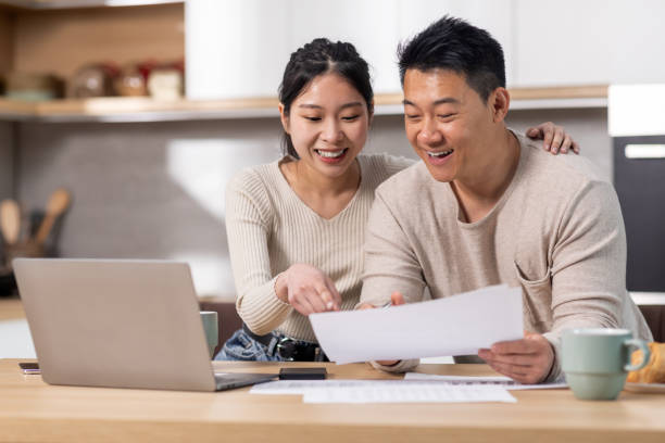 istock Cheerful asian spouses paying bills on Internet, using laptop 1471033503