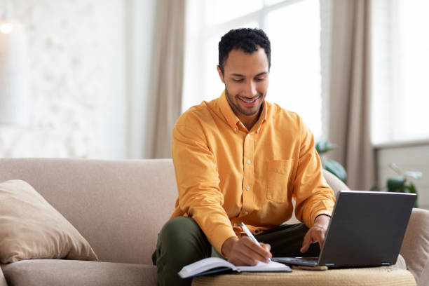 istock Portrait of smiling Arab man using laptop and writing 1471033567