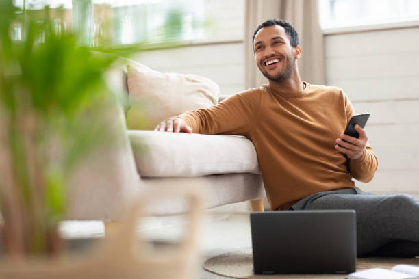 istock Young Arab man holding phone using pc at home 1471033930