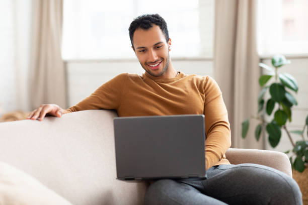 istock Arab man using laptop sitting on couch at home 1471033967