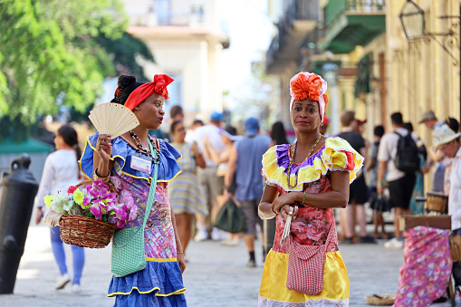 Havana, Cuba - February 2023: Cuban women in traditional clothing called 'Costumbrista' show the colonial times on Old Havana street on crowd of people background