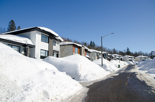 Luxury houses hidden behind snowbanks during day of winter