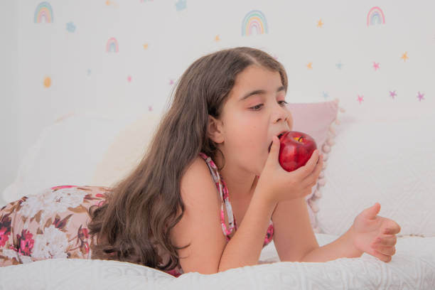 istock Girl lying in bed eating apple 1471037418