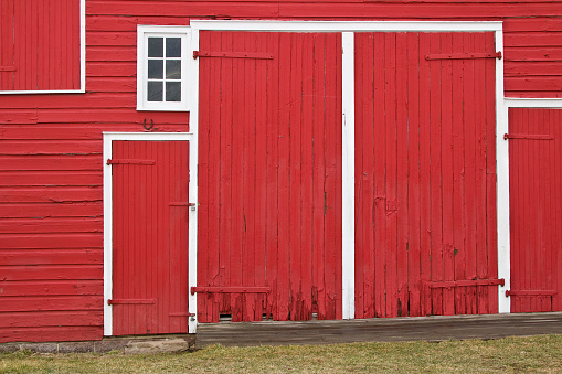 Front entrance of an old wooden farmhouse barn doors with metal wagon wheel 