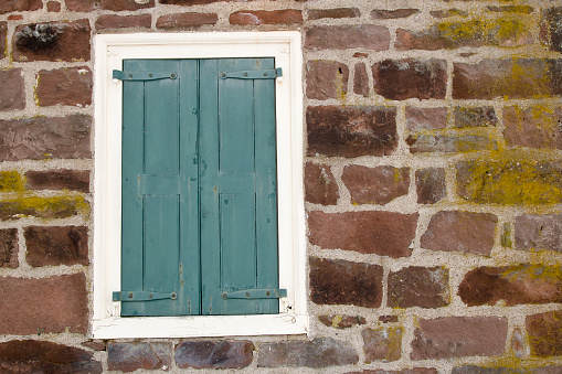 The old red brick fortress wall. There is a square window with a stone frame and iron bars. Background. Texture.