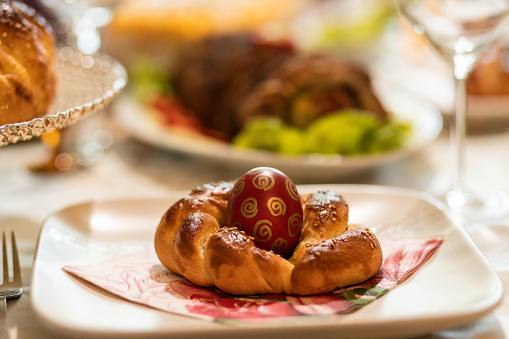 Realistic Easter family lunch. Cozy rustic Easter meal for the family. Easter egg in a homemade bun. Easter table decoration.