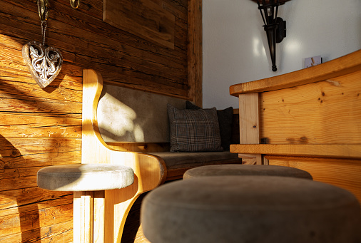 Sofa corner with a wooden wall of an Alpine restaurant, illuminated by the bright morning sun, Austria. High quality photo