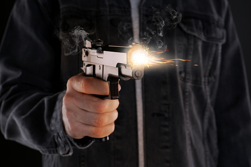 Man shooting handgun on black background, closeup