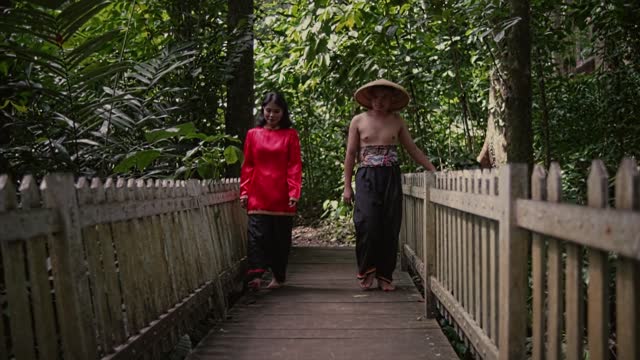 Vietnamese couple in traditional clothes walking while dating on a wooden bridge