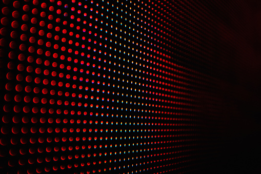 Abstract close-up view of a modern electronic billboard displaying a dark image with red dots.