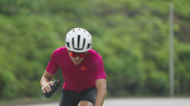 Thirsty Asian Chinese professional cyclist athlete drinking water during cycling