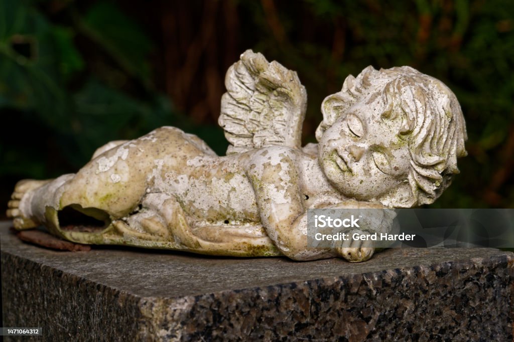 weathered small winged angel damaged and weathered small winged angel lies on tombstone Small Stock Photo