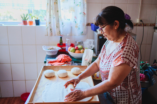 Portrait of an elderly latin woman cooking homemade bread in her kitchen.
